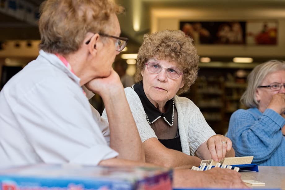 Two women playing Scrabble in a library.