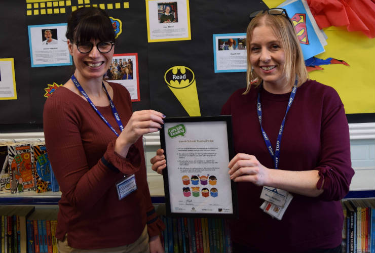 2 teachers in front of a school display board