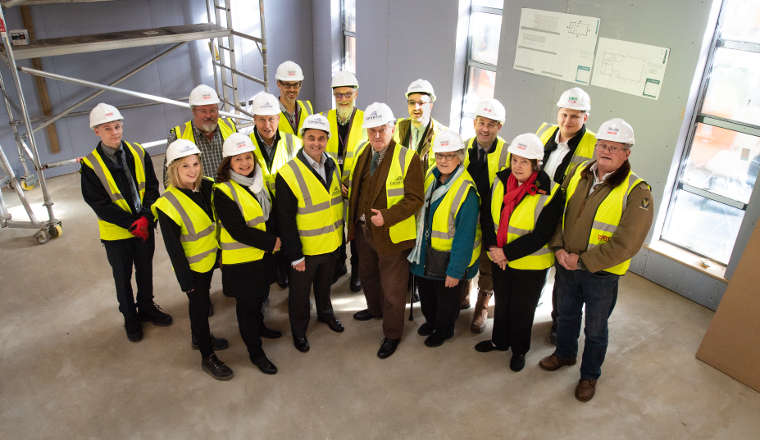 People in hard hats and high visibility jackets in a building that's still being completed