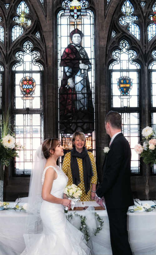 A couple getting married by a stain glass window