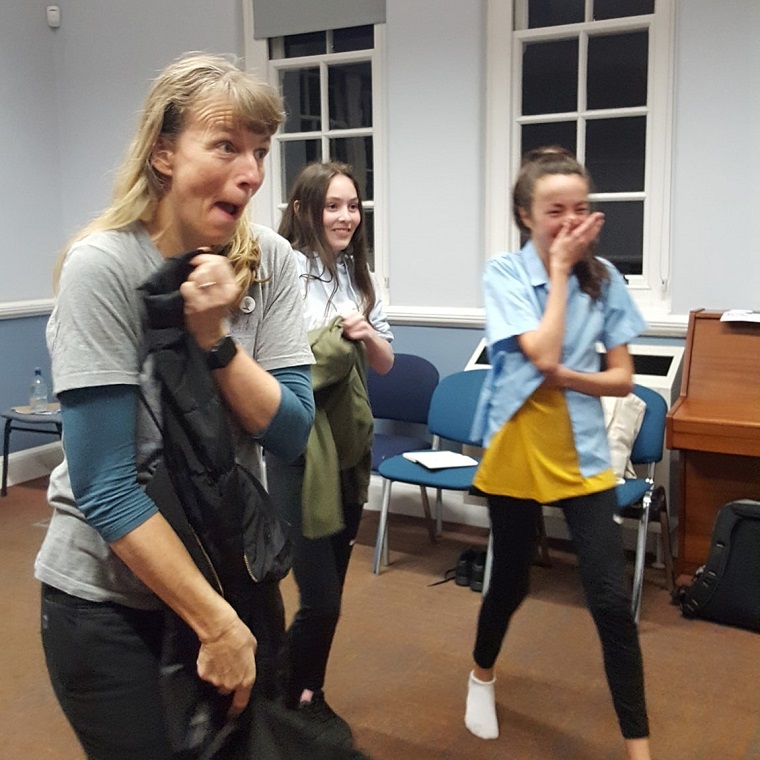 Woman and school children laughing and dancing