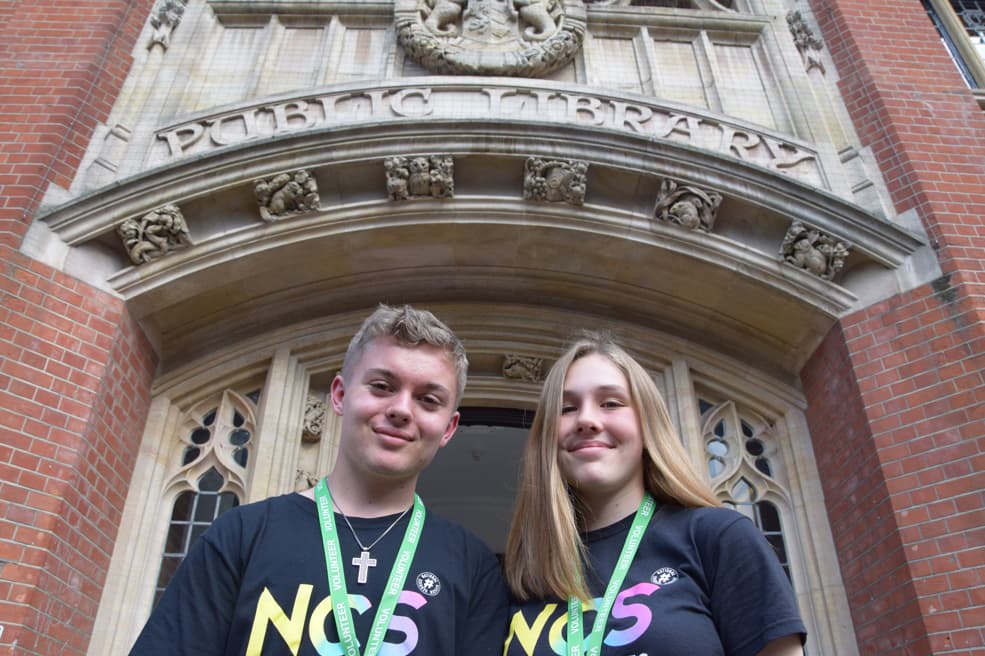 Two young people in T-shirts in front of Ipswich County Library.