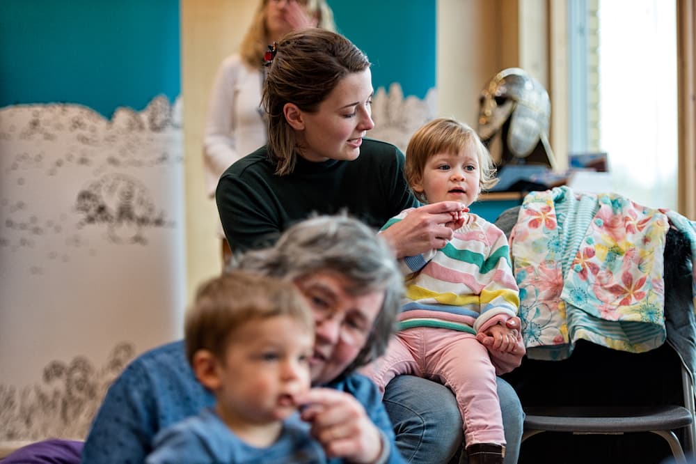 Parents and carers playing with young children in a library.