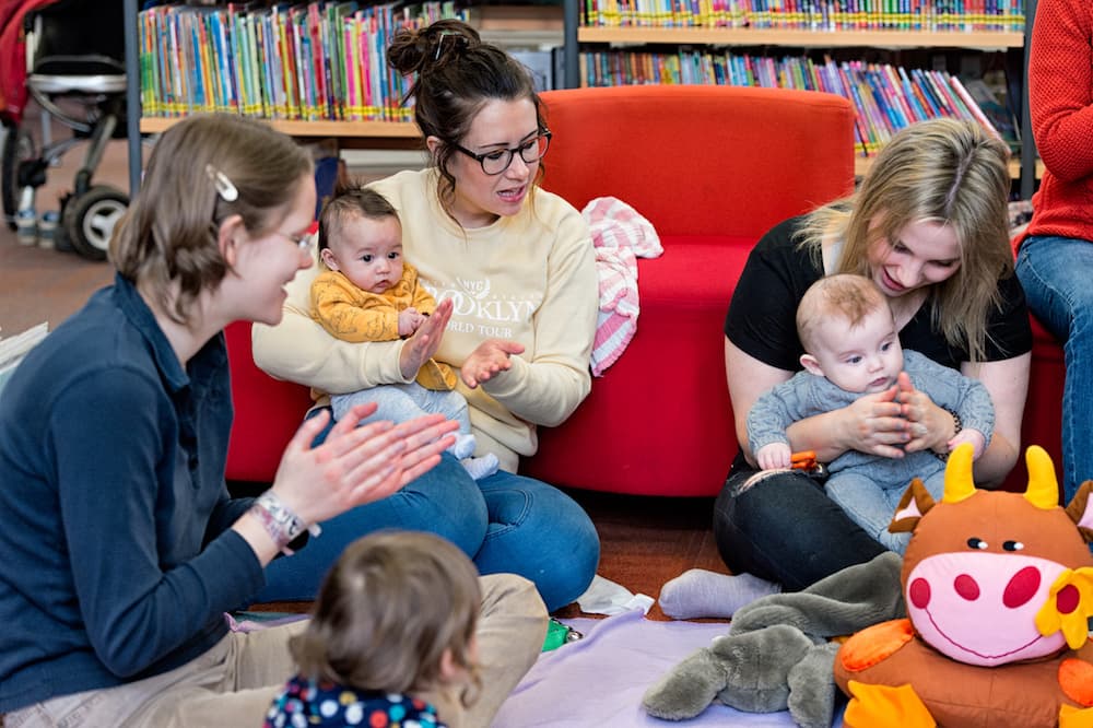 Parents and carers playing with babies in a library.