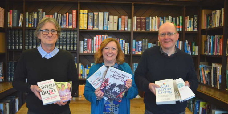 Alan Sterenberg, former Suffolk Libraries CEO Alison Wheeler and stock librarian Brandon King with some of the books from the new cancer collection.