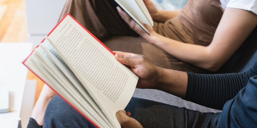 A man and a woman sitting side-by-side, reading books