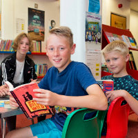 Two boys with books and a Summer Reading Challenge volunteer