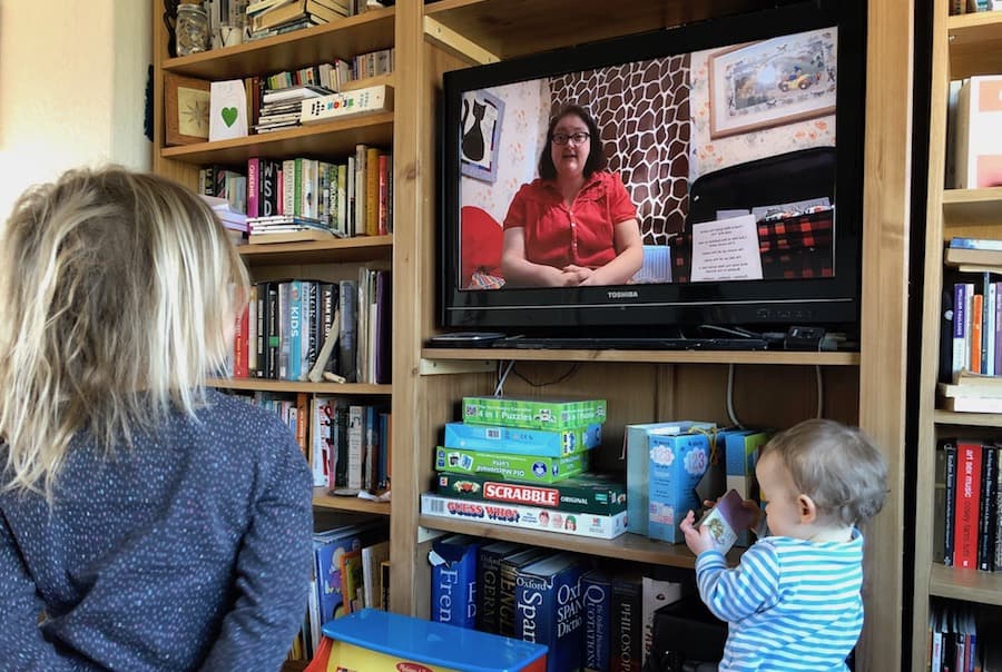 Child watching a woman tell a story on TV.