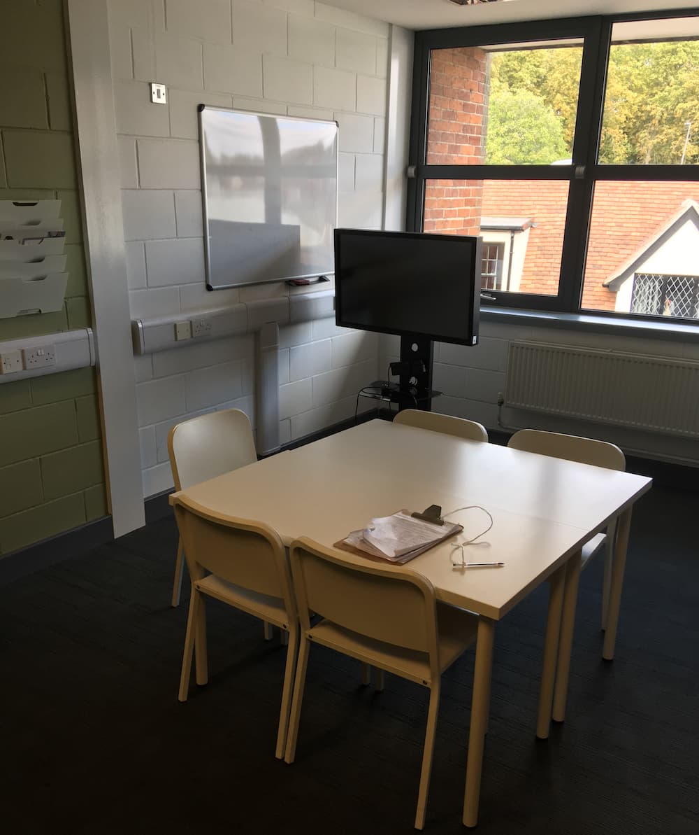 Room with table, chairs and a display screen.