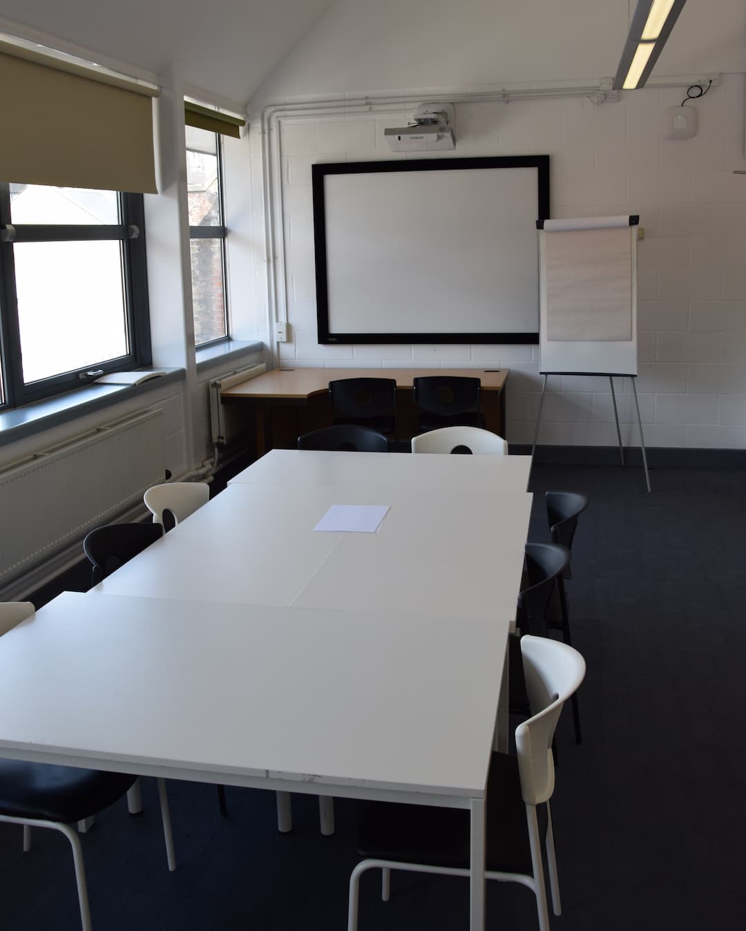 Table and chairs in front of a presentation screen.