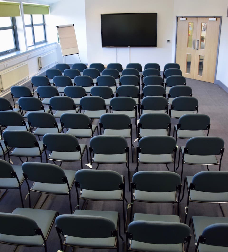 Large room chairs set in rows of six in front of a large display screen.